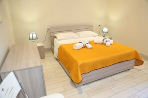 Une chambre d’hôtel comprenant un lit, deux tables de chevet, un bureau et deux lampes.