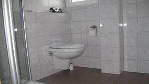 Casa de banho com sanita, cabine de duche e lavatório.