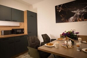 Een moderne keuken met donkere kastjes, een magnetron en een ontbijttafel compleet met borden, kopjes en een decoratief middelpunt.
