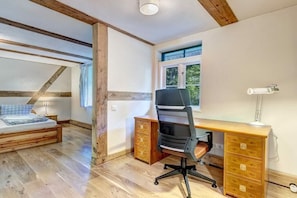 A bedroom with a wooden bed, a desk with a chair, and a window.