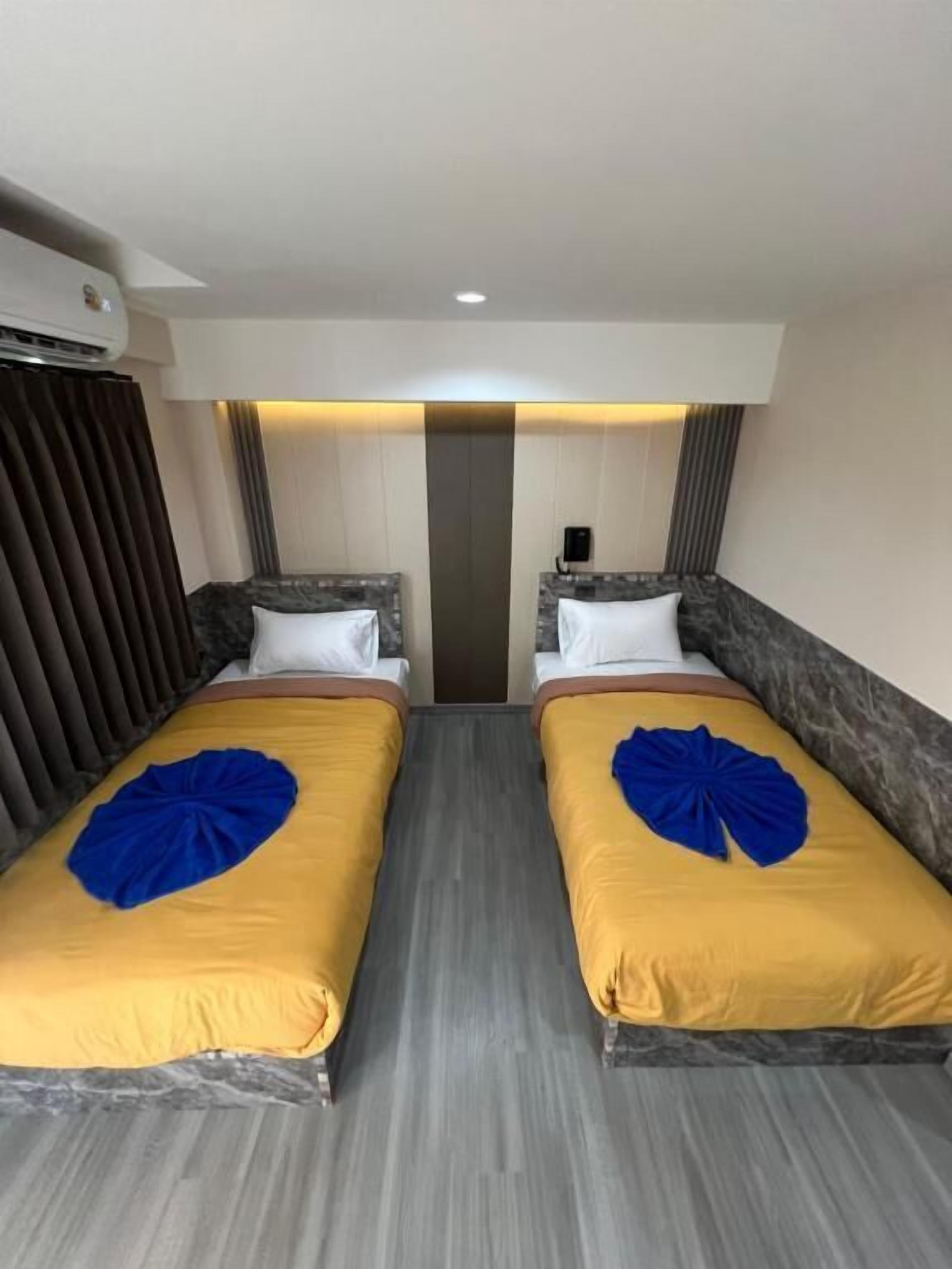 A hotel room with two beds, each with a headboard and pillow, and a central light fixture.