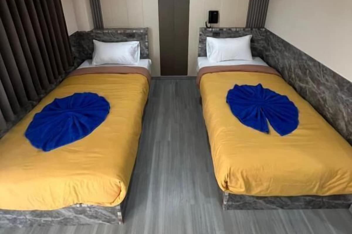A hotel room with two beds, each with a headboard and pillow, and a central light fixture.