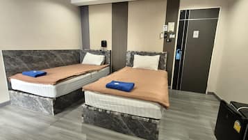 Habitación de hotel con dos camas, un teléfono y un cubo de basura.