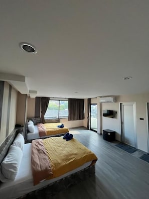 A hotel room with two beds, a large window, a door, and a small desk. - CK Residence Hat Yai (Chang Wat Songkhla)