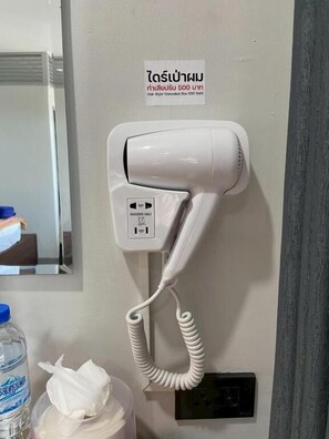 Habitación de hotel con secador de pelo y teléfono fijo en la pared.