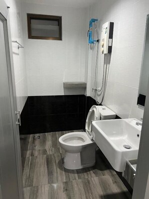 Un baño con inodoro, lavamanos y ducha.