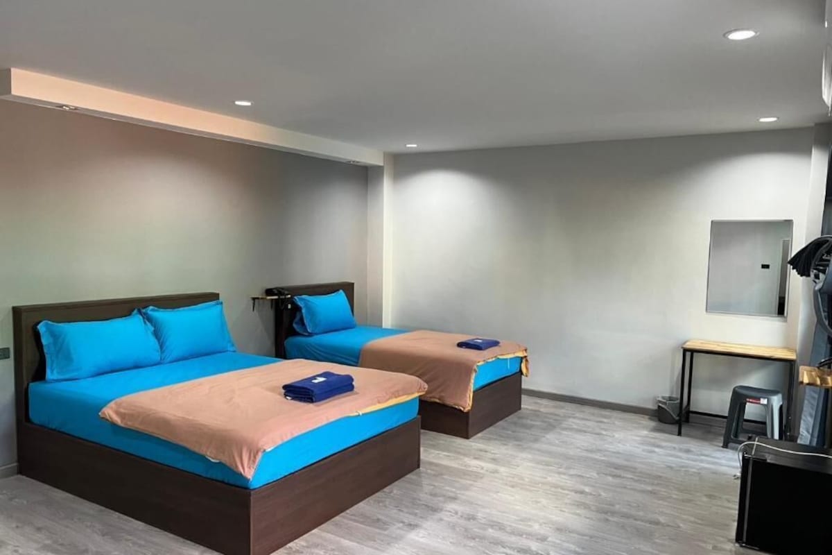 A hotel room with two beds, a desk, and a mirror.