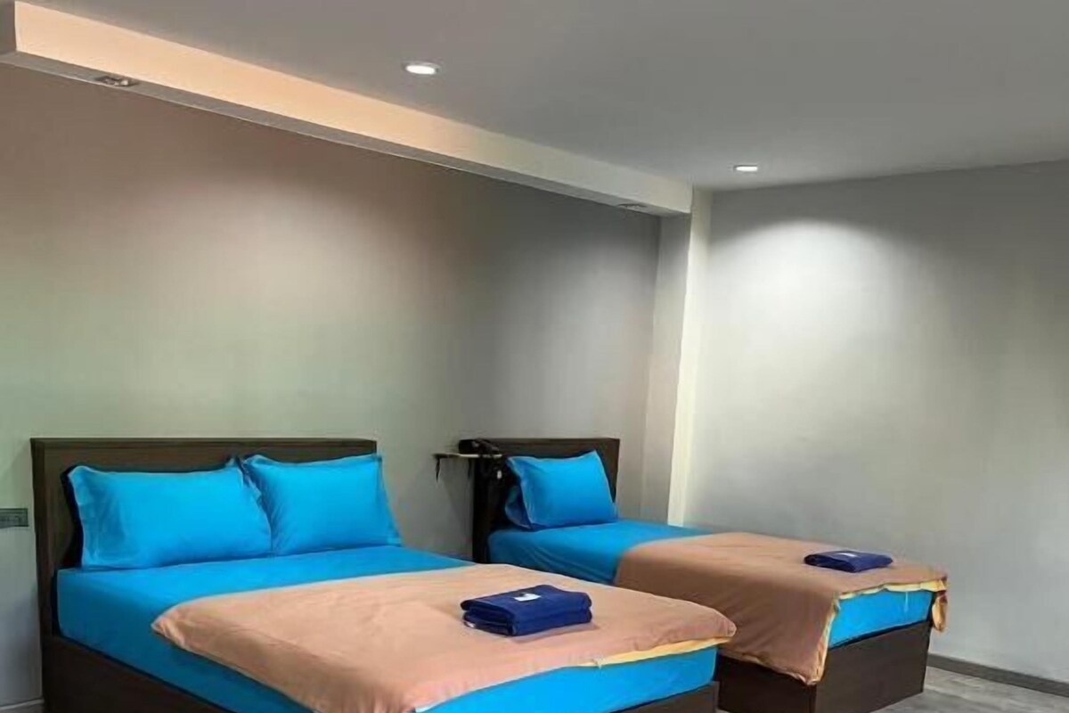 A hotel room with two beds, each with a blue headboard and a brown mattress.