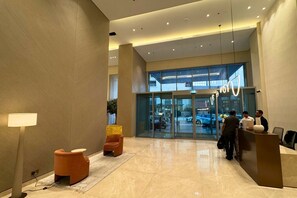 A hotel lobby with a reception desk, seating area, and a glass entrance. - Exquisite 1 Bed l Creek Skyline View l Gym & Pool (Dubai)