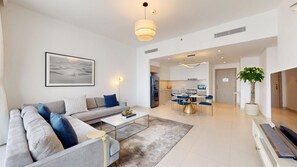 A modern living room with a sofa, coffee table, and a dining area with chairs and a table. - Exquisite 1 Bed l Creek Skyline View l Gym & Pool (Dubai)