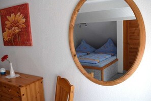 Un dormitorio con cama, cómoda de madera, espejo y un cuadro en la pared.