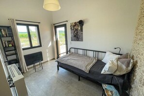Ein Schlafzimmer mit einem Bett, einem Heizkörper, einem Fenster, einem Bücherregal und einem an der Wand hängenden Bild.