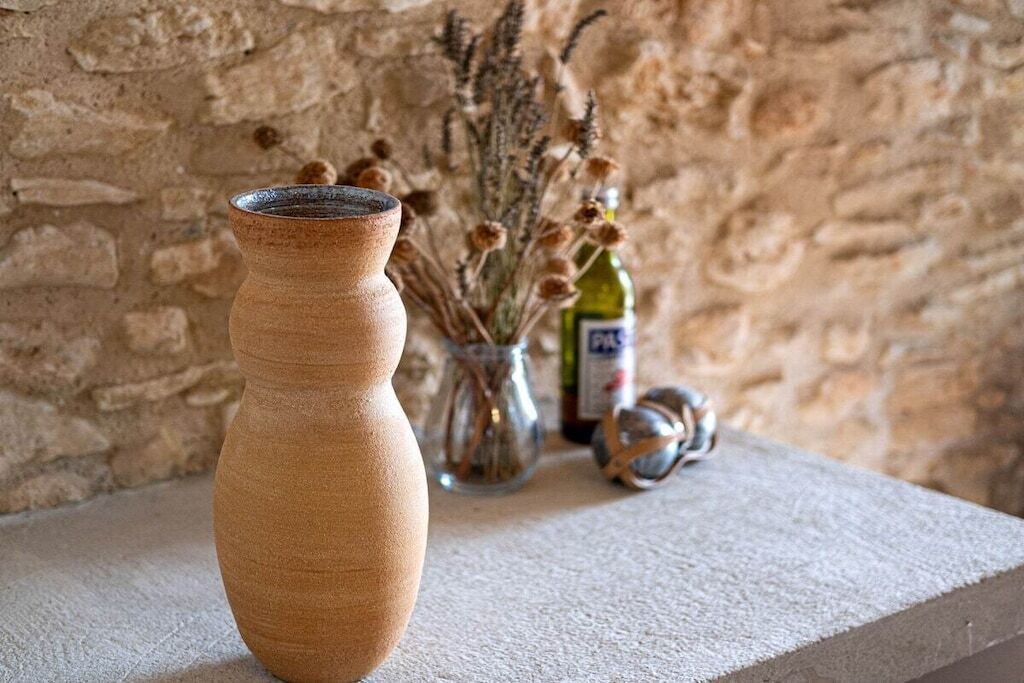 A terracotta vase on a textured stone ledge with a rustic stone wall background.