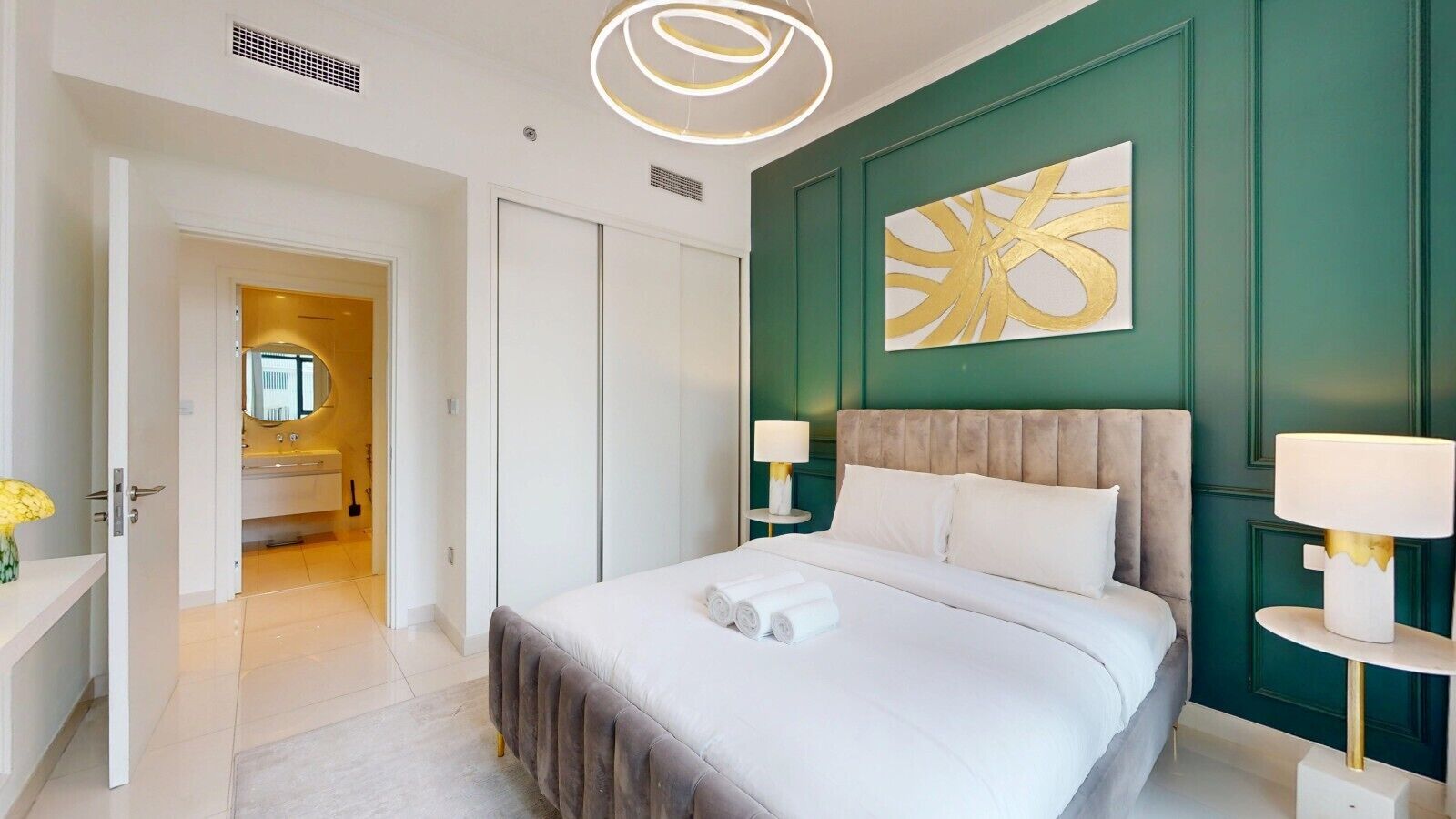 Una habitación de hotel con una cama, mesitas de noche, un espejo y una pared de acento verde.