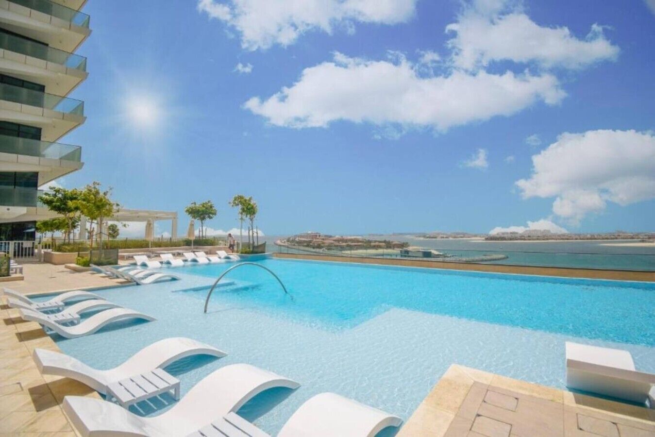 Una piscina con sillas de descanso y vista al mar.