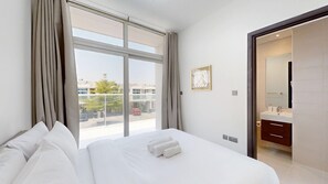 A hotel room with a large bed, a bathroom with a mirror, and a view of the outside. - Private 3 Bed Villa with Garden l Malibu Waterpark (DAMAC Hills 2)