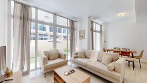 A modern living room with a sofa set, a coffee table, and a dining area with chairs and a table. - Private 3 Bed Villa with Garden l Malibu Waterpark (DAMAC Hills 2)