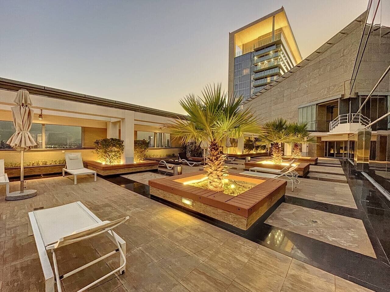 A rooftop terrace with seating areas, a pool, and a modern building in the background.