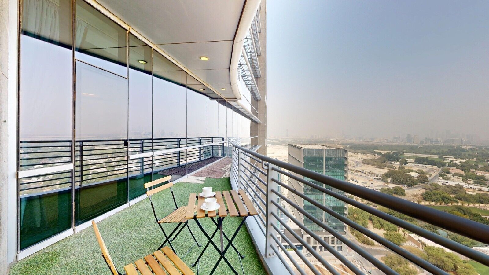 A balcony with a table and chairs, a view of the cityscape, and a railing.