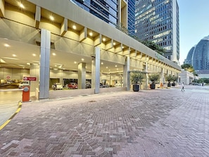 A hotel entrance with a covered outdoor area, a parking lot, and a cityscape in the background. - Bustling 2 Bed in DIFC l near Museum of the Future (DIFC)
