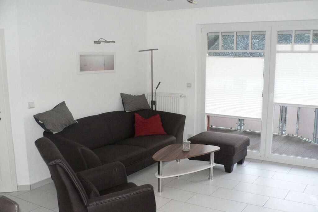 Una sala de estar moderna con un sofá, reposapiés y una mesa de centro.