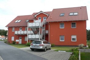 Ein rotes, zweistöckiges Gebäude mit einem geparkten Auto davor.