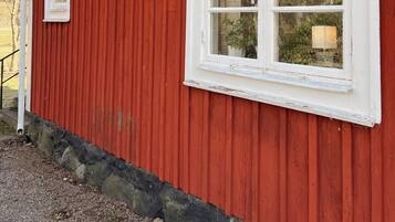 Un bâtiment rouge avec des fenêtres à encadrement blanc et des fondations en pierre.