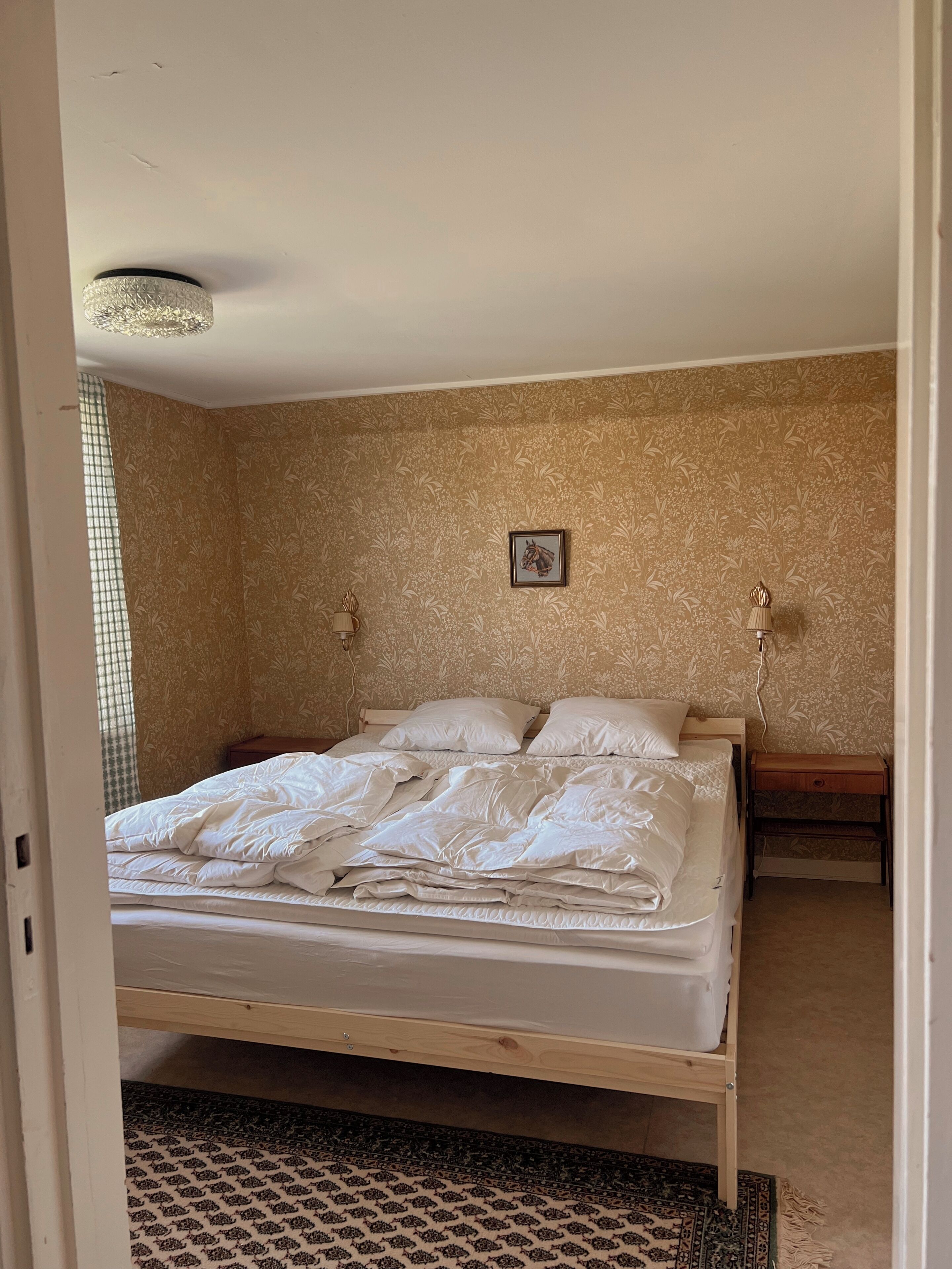Une chambre à coucher avec un lit, une table de chevet, une lampe et un tapis à motifs.