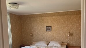 A bedroom with a bed, a nightstand, a lamp, and a patterned carpet.