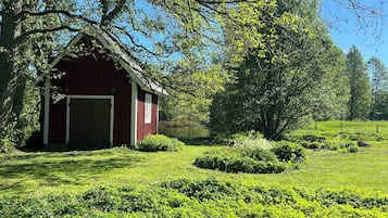 A red barn with a white door, surrounded by lush green grass and trees.