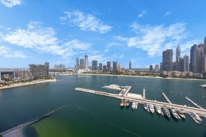 A marina with boats docked, a city skyline in the background, and a clear sky. - Upgraded 2 Bed l Beach View l Emaar Beachfront (Emaar Beachfront)