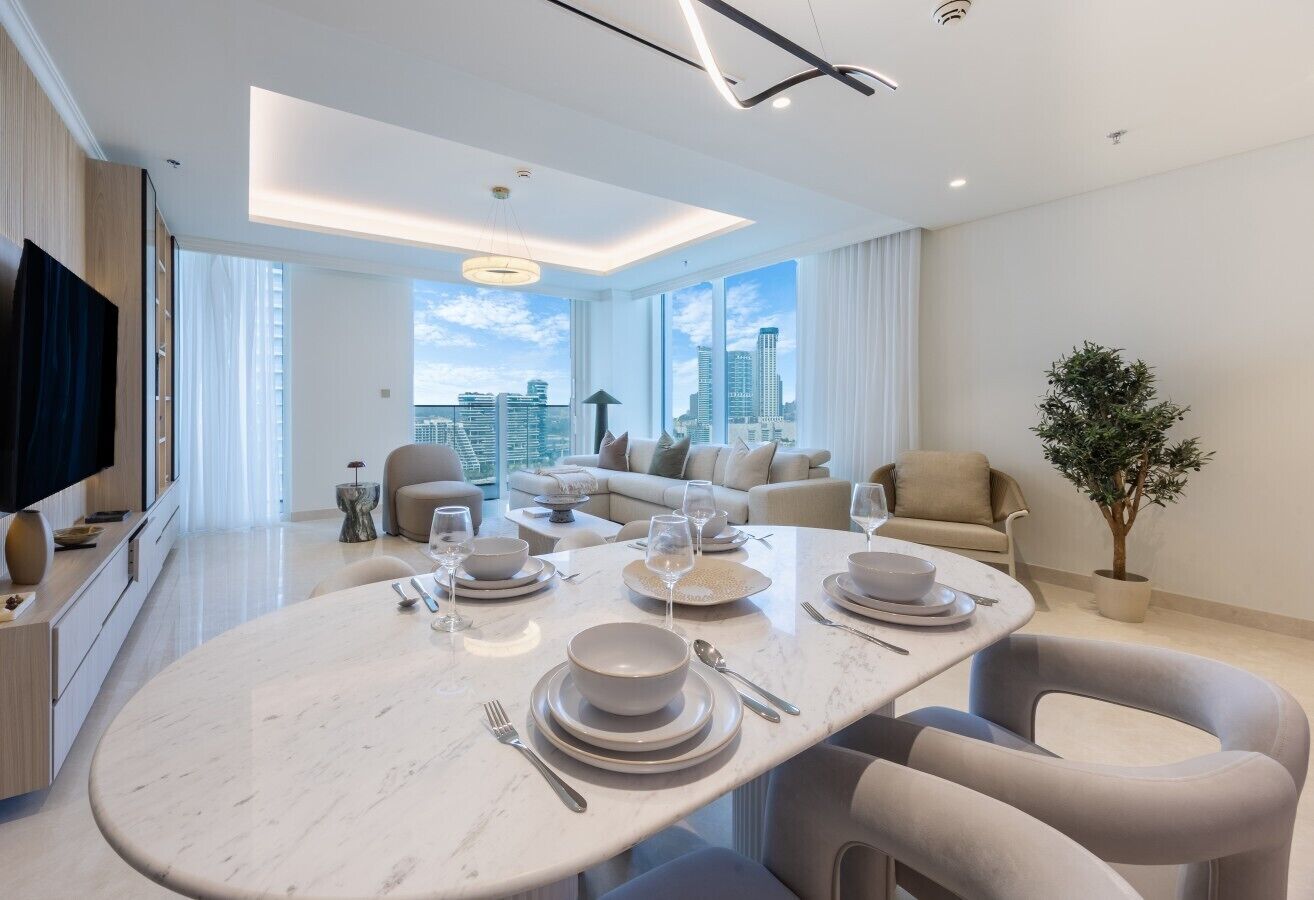 A modern dining area with a round table set for four, a city view, and a minimalist decor.