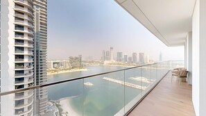 A high-rise building with a balcony overlooking a marina and city skyline. - Upgraded 2 Bed l Beach View l Emaar Beachfront (Emaar Beachfront)