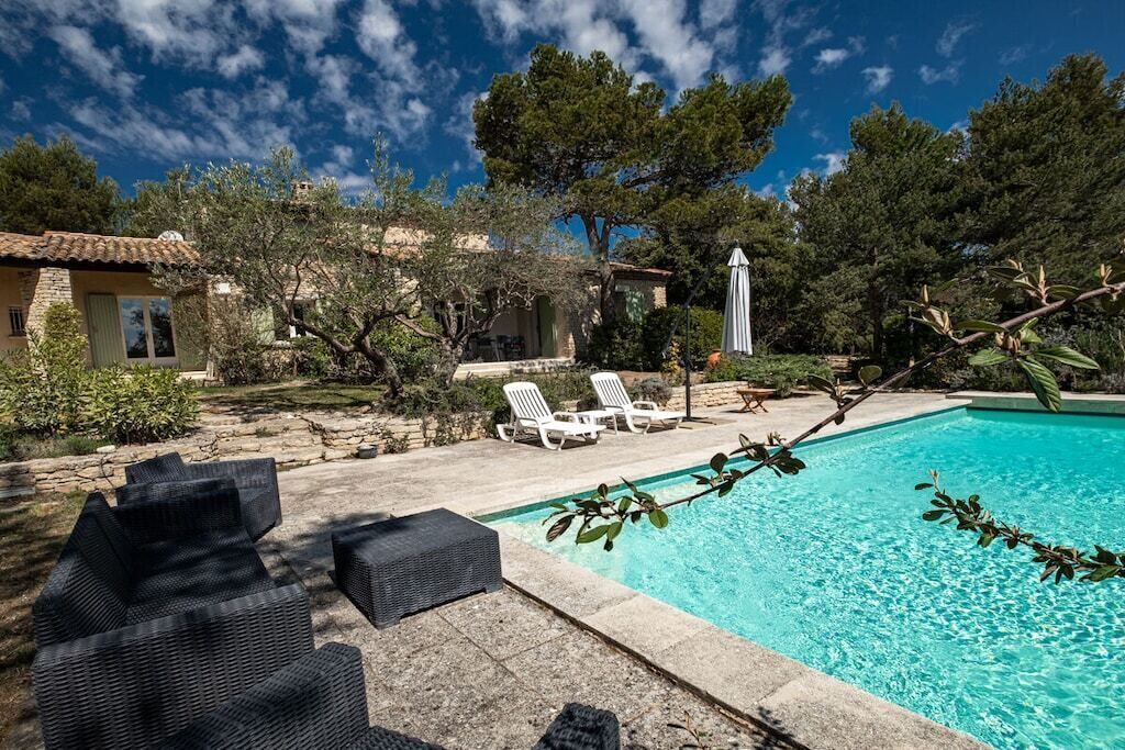Une piscine avec des chaises longues, un chemin de pierre et un bâtiment doté d’un toit en tuiles.