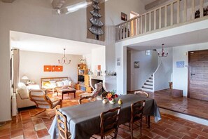 A spacious living area with a dining table, seating, a fireplace, and a staircase leading to an upper level. - Holiday home in Murs with swimming pool (Murs)