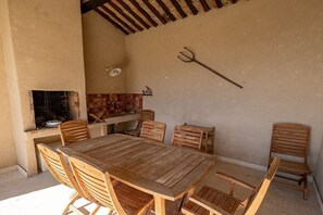 A wooden table and chairs set up outdoors with a grill and a tiled backsplash. - Holiday home in Murs with swimming pool (Murs)