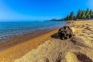 Una playa con agua cristalina, una orilla arenosa y una roca grande.