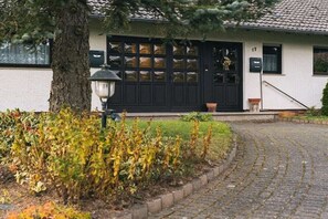 Un immeuble avec une porte noire, une plaque de numéro et une allée pavée.