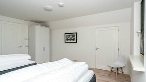 Quarto com duas camas, uma escrivaninha e uma cadeira.