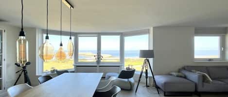 Un salon moderne doté d’une grande table, de sièges confortables et offrant une vue sur l’extérieur.