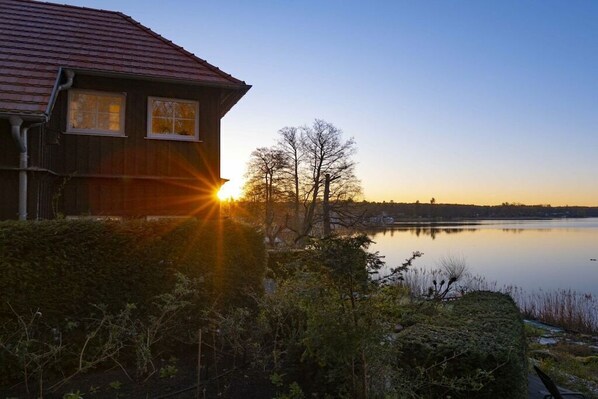 A house with a red roof and a view of a calm lake at sunset. - ||-------------------at Schlabornsee-------------------|| (Zechlinerhütte)