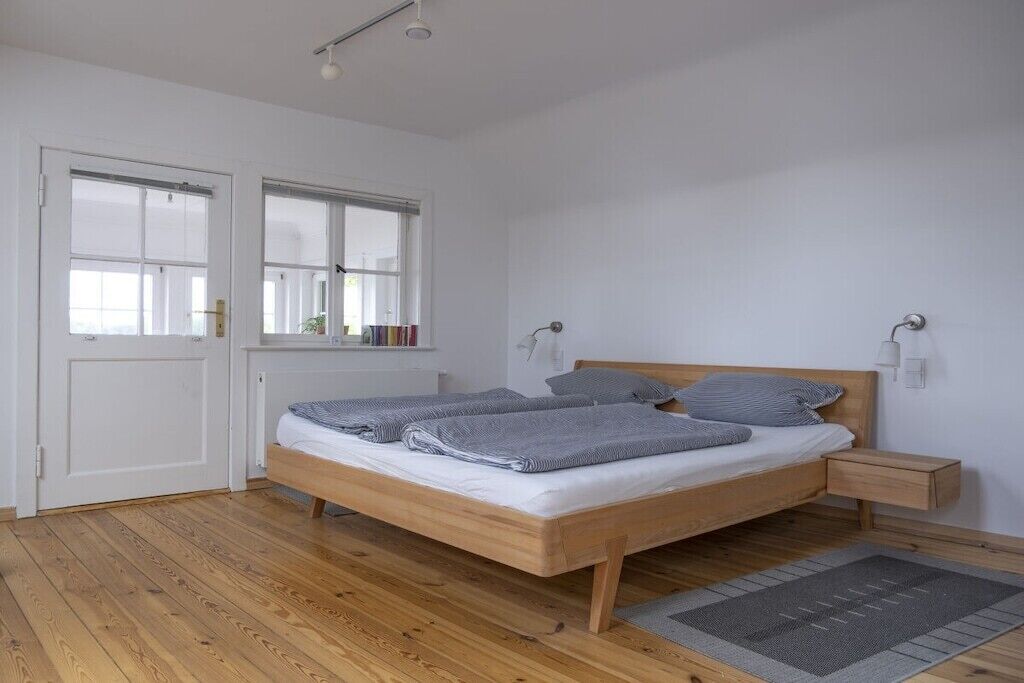 A bedroom with a wooden bed, bedside tables, a window, and a door.