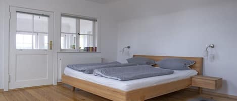 A bedroom with a wooden bed, bedside tables, a window, and a door.