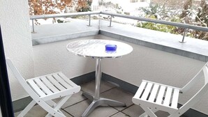 A balcony with a round table and two white chairs.