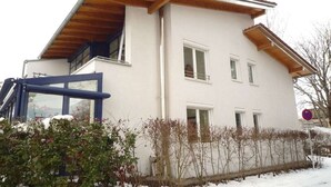 A two-story building with a balcony, a garage, and a snow-covered ground.