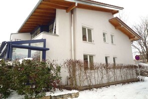 A two-story building with a balcony, a garage, and a snow-covered ground.