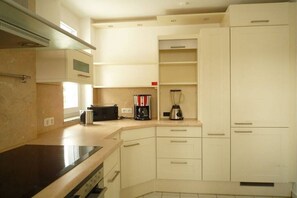 Una cocina con estufa, microondas y cafetera.