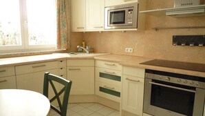 A kitchen with a microwave, oven, and a window with curtains.