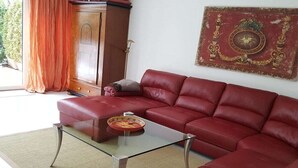 A red leather sofa, a glass coffee table, and a decorative wall piece in a living room.