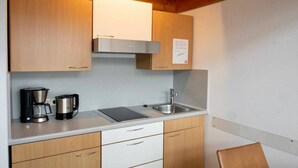 A compact kitchen with wooden cabinets, a stainless steel sink, and a coffee maker. - Holiday apartment with 1 bedroom (Lindau (Bodensee))
